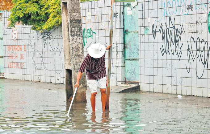 No bairro de Jardim Brasil, em Olinda, um homem ainda se arrisca ao tentar passar pela rua totalmente alagada (MARINA TORRES/DP FOTO)
